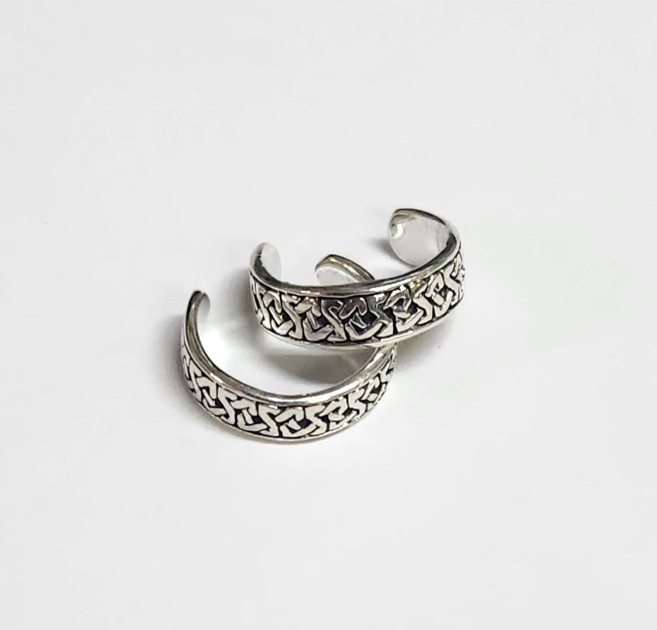 Pair of silver ear cuffs on a light gray background