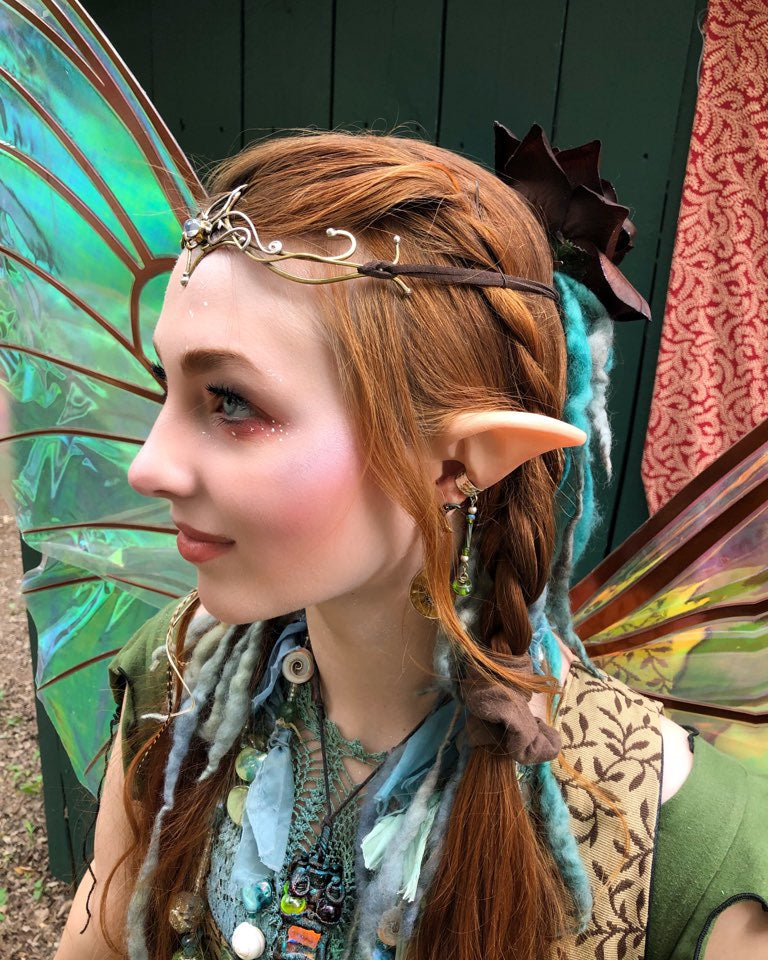A person wearing fantasy elf ears prosthetic as well as fairy wings