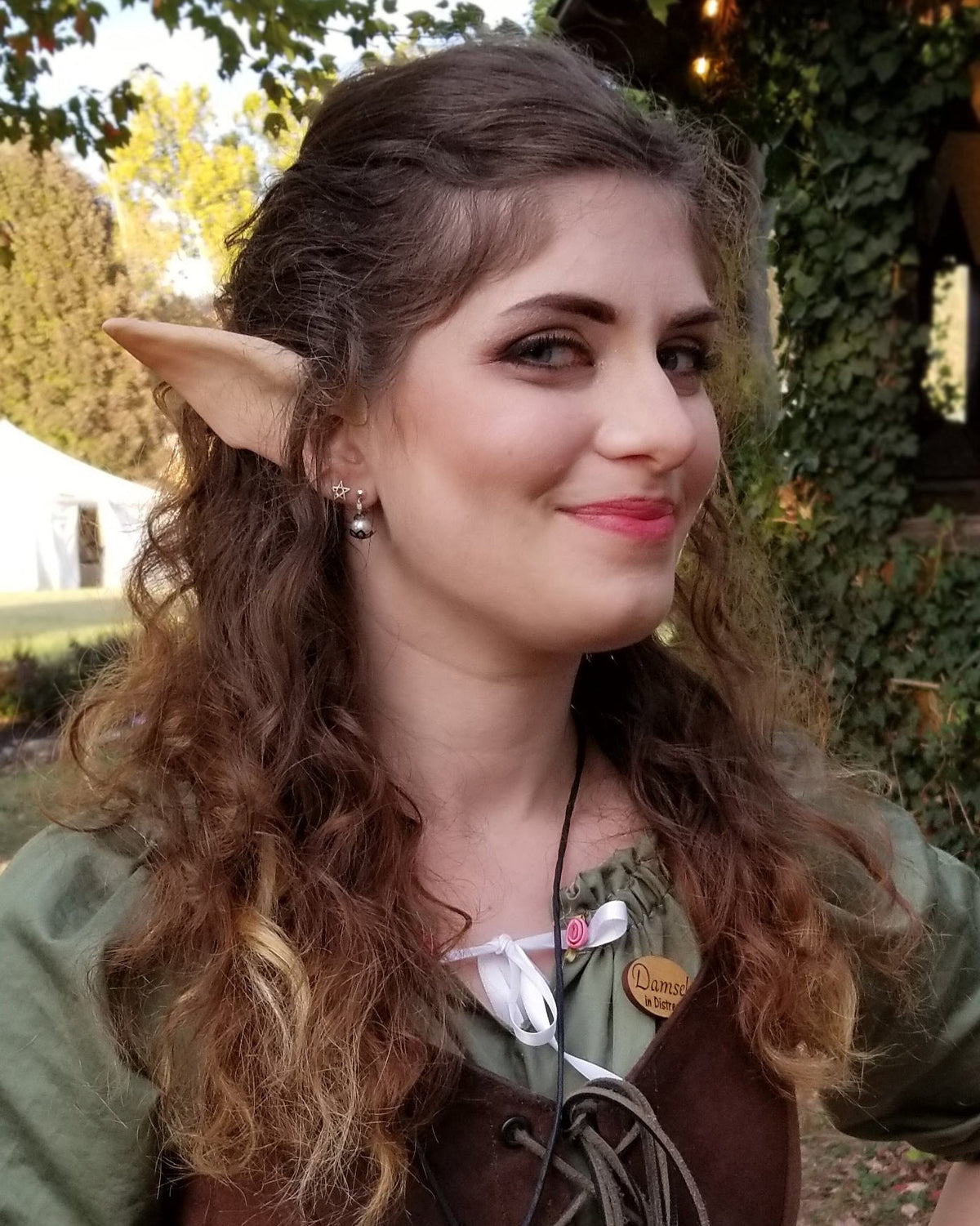 A person wearing elf ears with a green and brown costume designed to resemble an elf character.