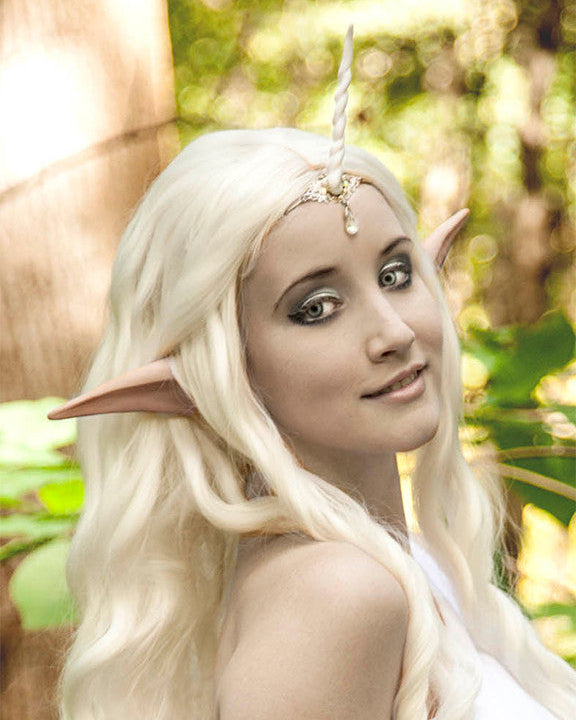A person with a costume featuring large anime elf ears, with a background of trees.