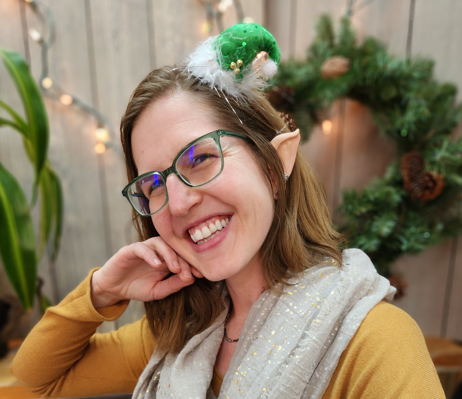 A person smiling and wearing elf ears with a hat.